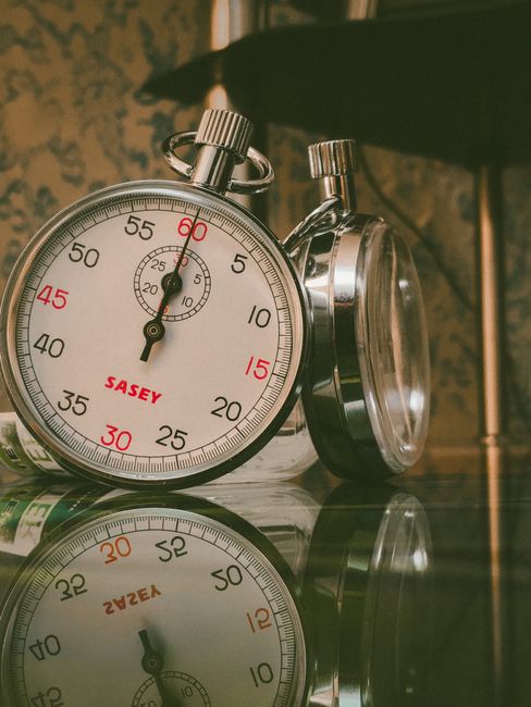 A detailed view of a classic analog stopwatch with reflection on a glass surface.