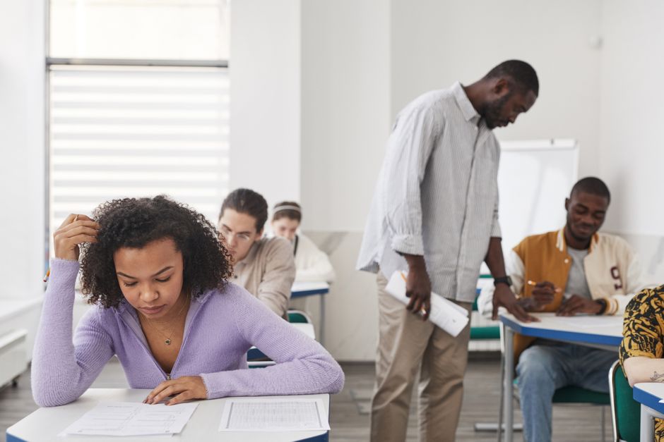 Anxiété face aux examens : ce que montrent les études de 2025 et 2026 A diverse group of students taking an exam in a modern classroom with a teacher supervising.
