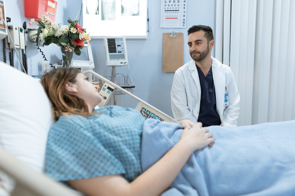 A doctor comforts a patient in a hospital room, emphasizing professional care.