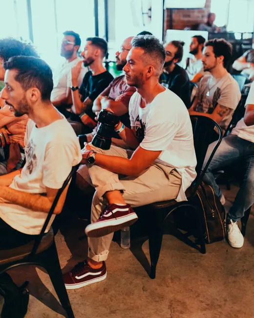 A group of adults attentively listening at an indoor seminar or conference.