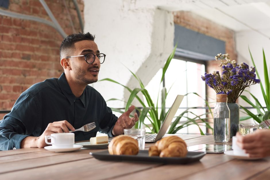 Trouble formel de la pensée : quand le discours perd son fil A man in glasses engaging in conversation over brunch with croissants and coffee.