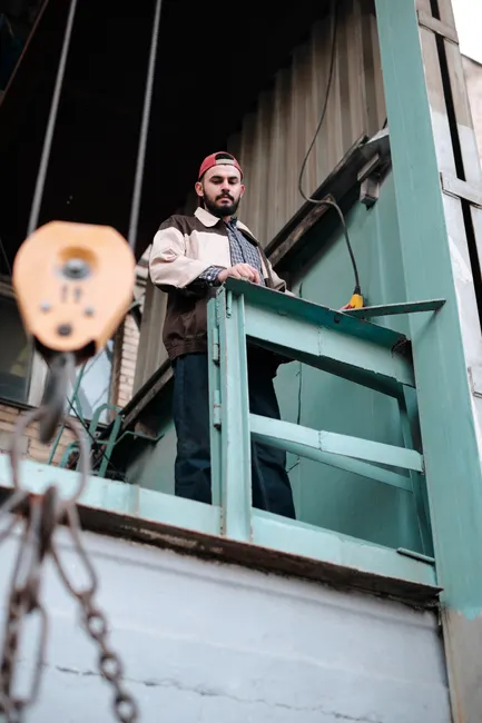 A man stands on an elevated platform at a construction site, observing the area.