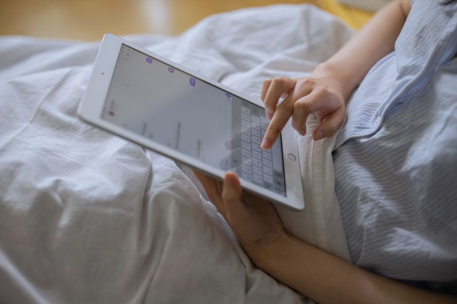 Autisme non parlant : aider à communiquer sans confondre silence et absence de pensée A person comfortably using a digital tablet indoors, typing on a virtual keyboard.