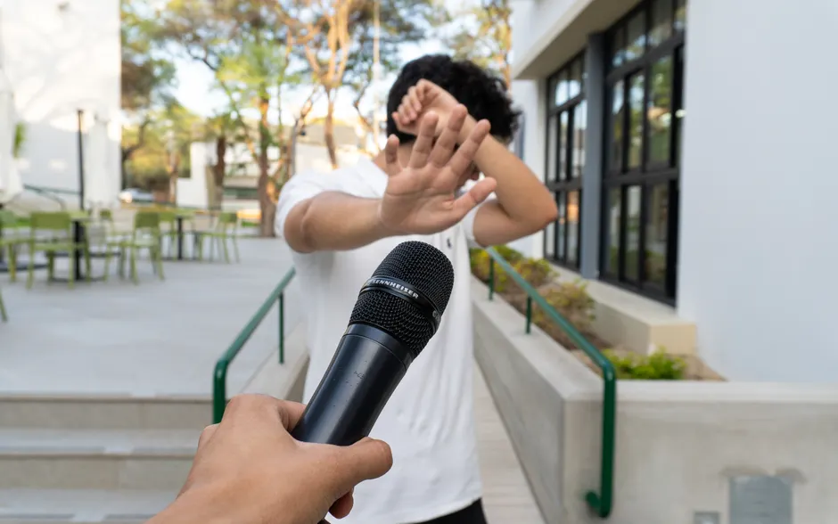 A person outdoors in Piura avoiding a microphone, signaling discomfort or reluctance.