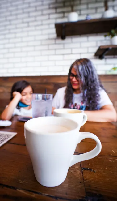 A relaxed cafe setting with a mother and daughter enjoying coffee and quality time together.