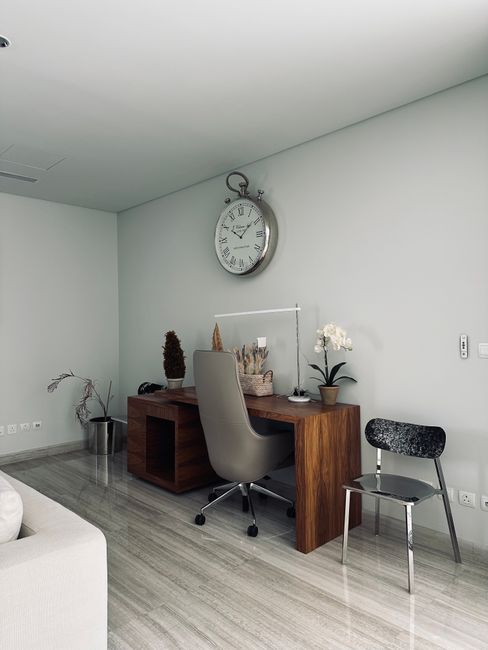 A sleek office space featuring a wooden desk with decor and a vintage clock.