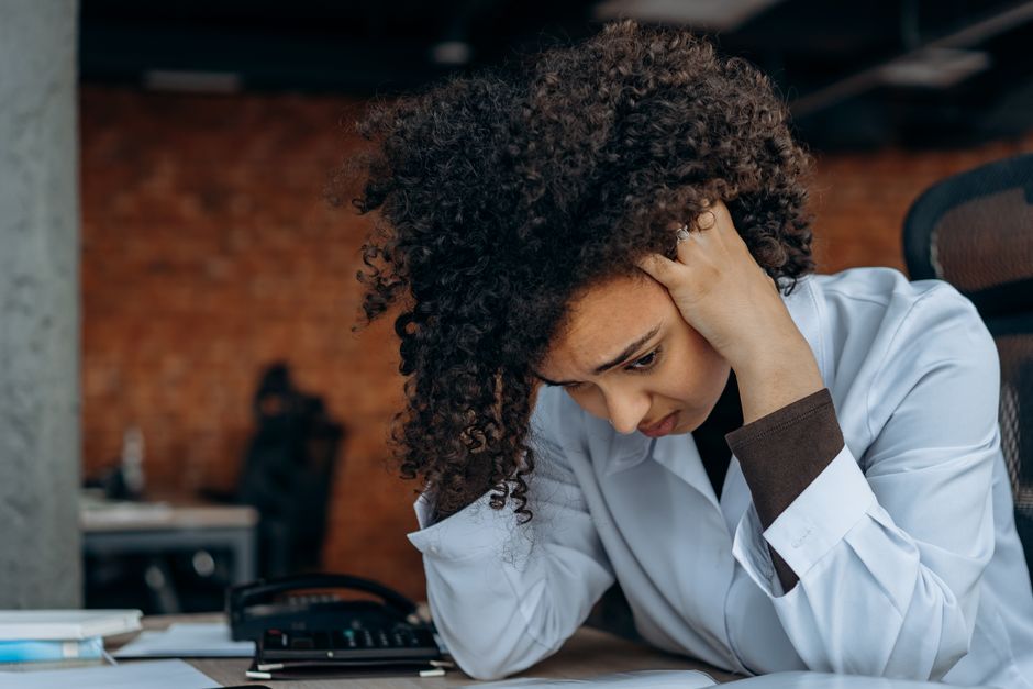 Anxiété au travail : choisir un métier sans réduire sa vie à ses symptômes A woman in an office appears stressed while reviewing documents at her desk.