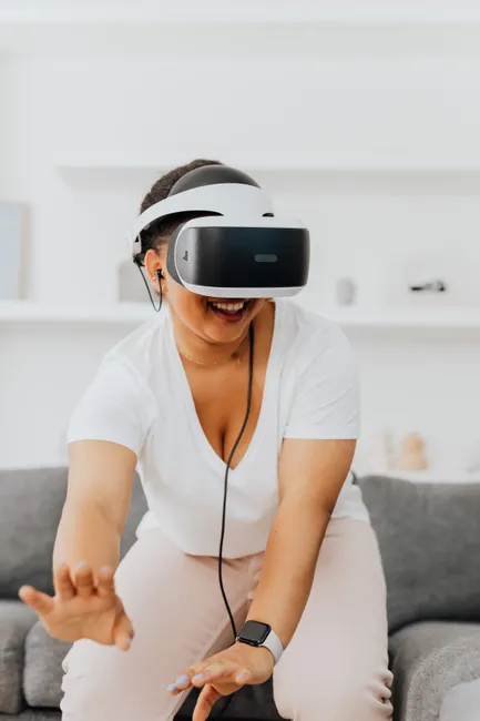 A woman wearing a VR headset immerses herself in a virtual reality game indoors.