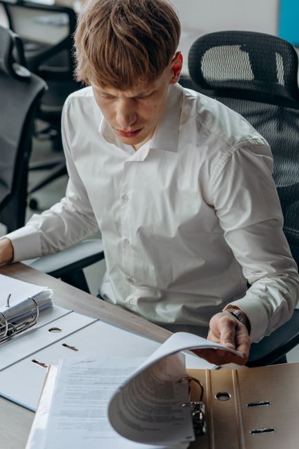 An office worker in a white dress shirt reviewing documents at a desk, emphasizing focus and productivity.
