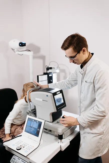 An optician examines a child's vision using advanced medical equipment in a modern clinic.
