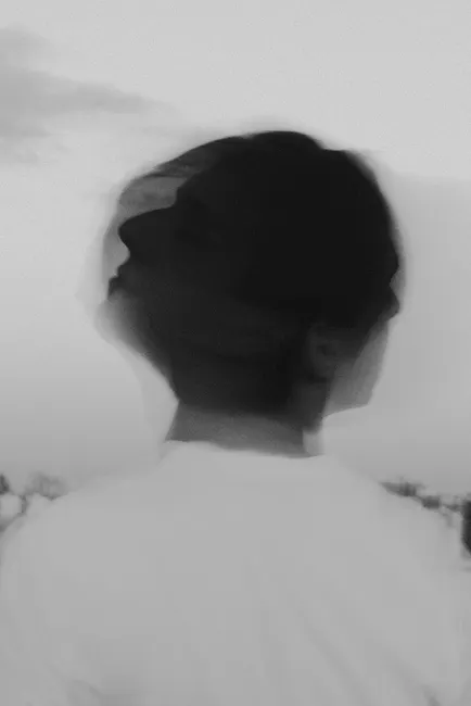 Artistic black and white portrait of a person with a blurred motion effect, creating a conceptual and dreamy look.