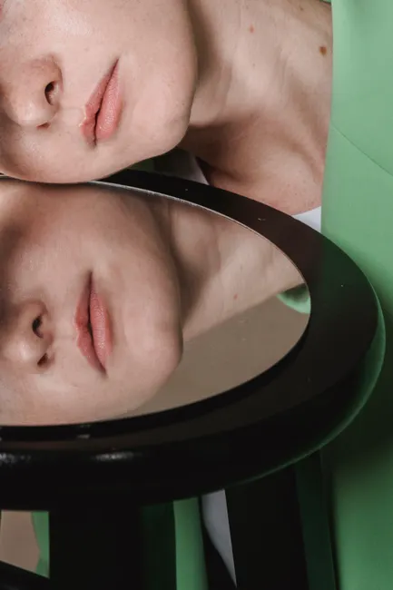 Artistic portrait of a person's reflection in a round mirror creating a creative composition.