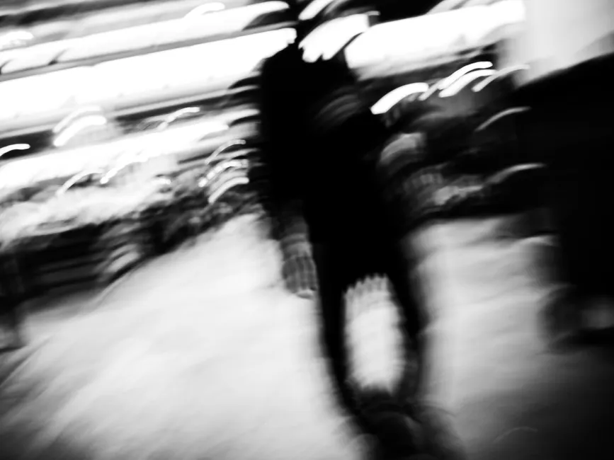 Irritabilité et trouble bipolaire : distinguer l’agitation sans tout confondre Blurred silhouette of a person walking in a busy urban setting, captured in black and white.