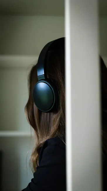 Brunette woman wearing headphones, relaxing indoors, enjoying music.
