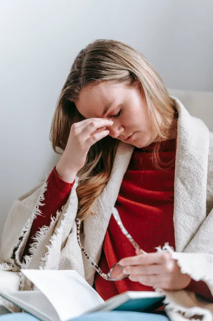 Caucasian woman holding head in pain, indicating a headache or migraine issue.