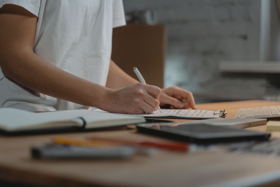 Perfectionnisme et dépression : quand l’autocritique prend le dessus Close-up of individual writing on a clipboard at a desk with office supplies.