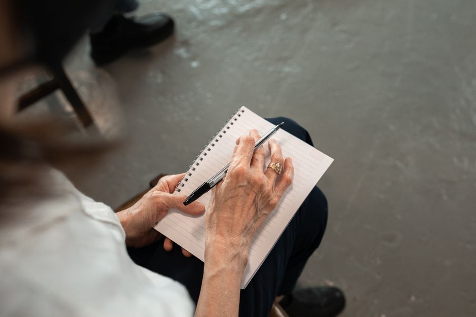 Schizophrénie et écriture : ce qu’une page peut montrer et ce qu’elle ne dit pas Close-up of senior hands with pen writing in a spiral notebook. Personal notes concept.