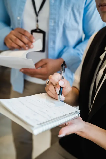 Close-up of two professionals discussing and writing notes in a business meeting.