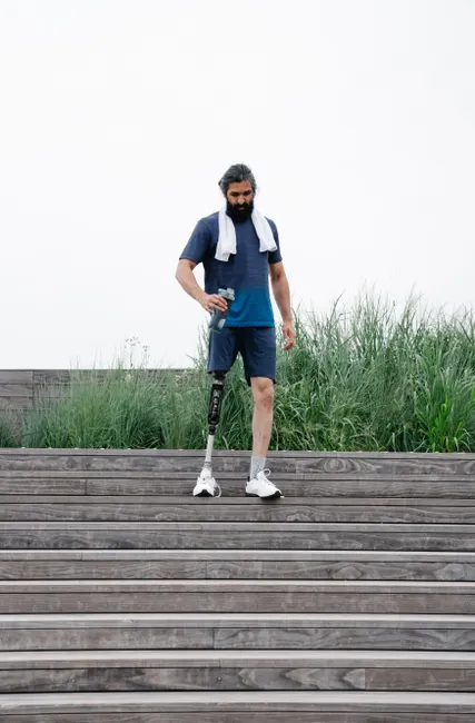 Confident man with prosthetic leg walking down outdoor stairs, embracing active lifestyle.