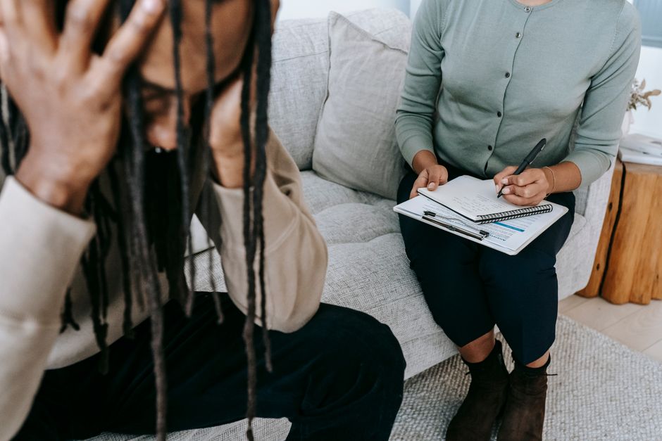 TOC et anxiété généralisée : ce que distinguent les études de 2025 et 2026 Crop concerned African American male sitting on sofa with female psychologist and holding head in hands in dismay during psychotherapy session