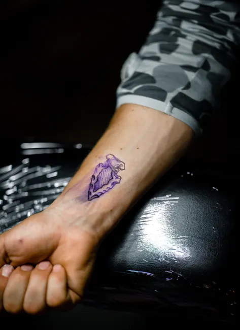 Detailed close-up of a tattoo design on a person's wrist during the inking process.