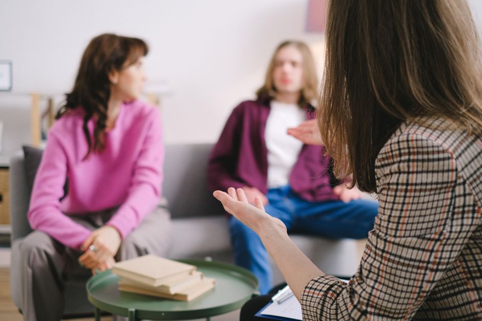 Soutien social et bien-être psychologique : la bonne aide compte plus que la quantité Engaged counseling session with three adults discussing together in a cozy indoor setting.