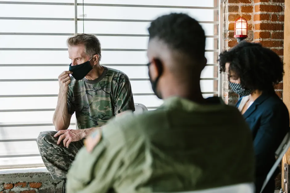 Military veterans in a therapy session, supported by a counselor, focusing on mental health.