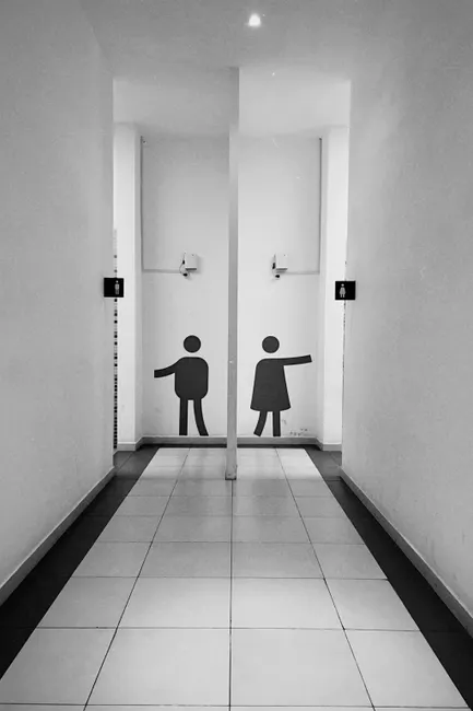 Minimalist black and white corridor with restroom signs in Almaty's public building.
