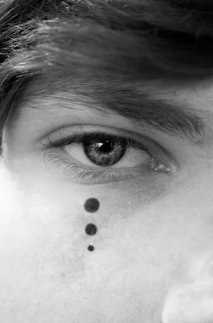 Monochrome close-up of an eye with artistic dots on the face, emphasizing vision and expression.