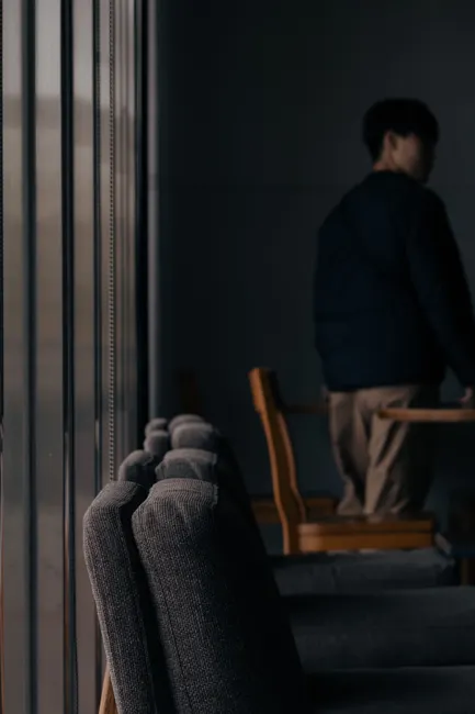 Moody, dimly lit room featuring cozy seating and a silhouetted person in the background.