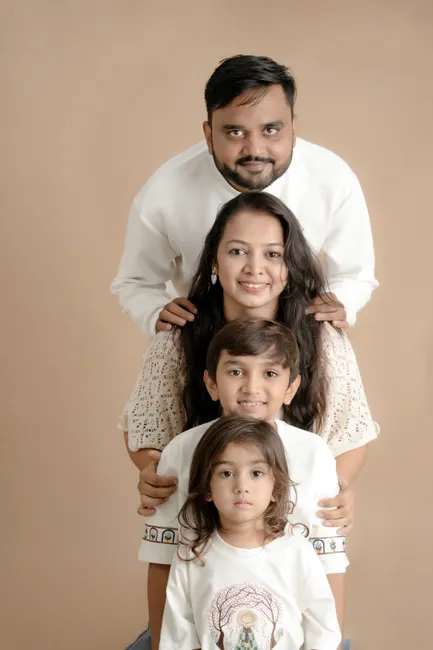 Portrait of a cheerful family of four posing against a brown backdrop.