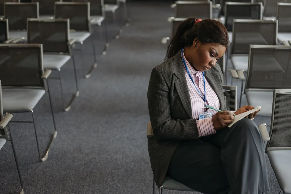 Professional woman writing notes in a quiet conference setting.
