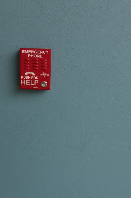 Red emergency phone mounted on a blue wall, offering help with a simple push.