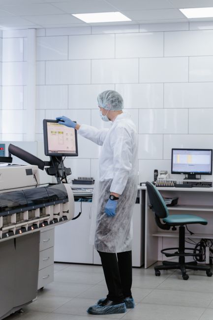 Scientist in protective gear analyzing data on a monitor in a modern laboratory setting.