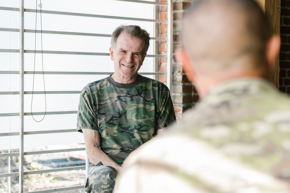 Prévenir le suicide chez les vétérans : ce que montrent les études avant la crise Senior and fellow military veterans engaging in a supportive therapy session indoors.