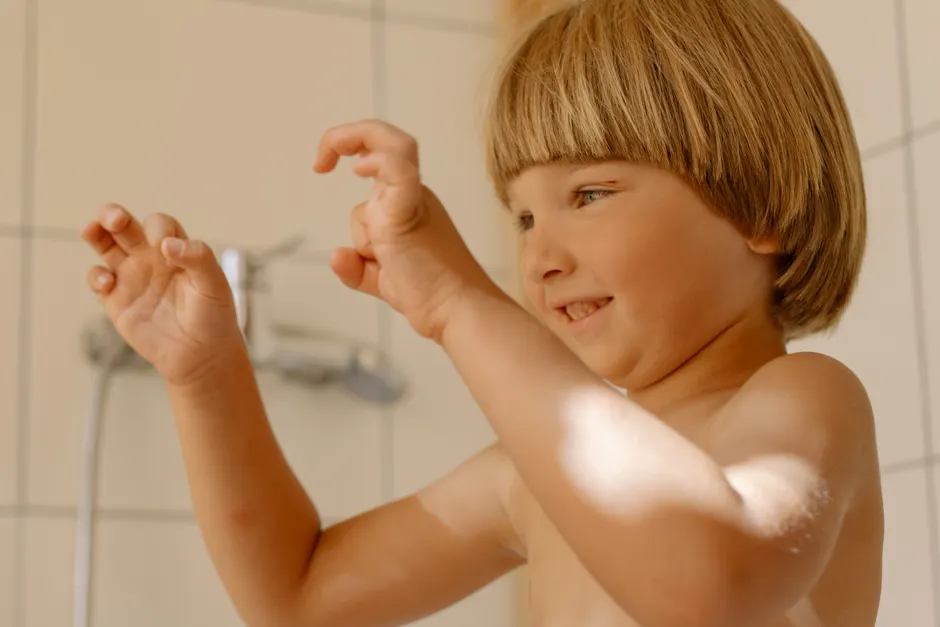 Smiling caucasian child with blond hair enjoying playtime in a bright bathroom.