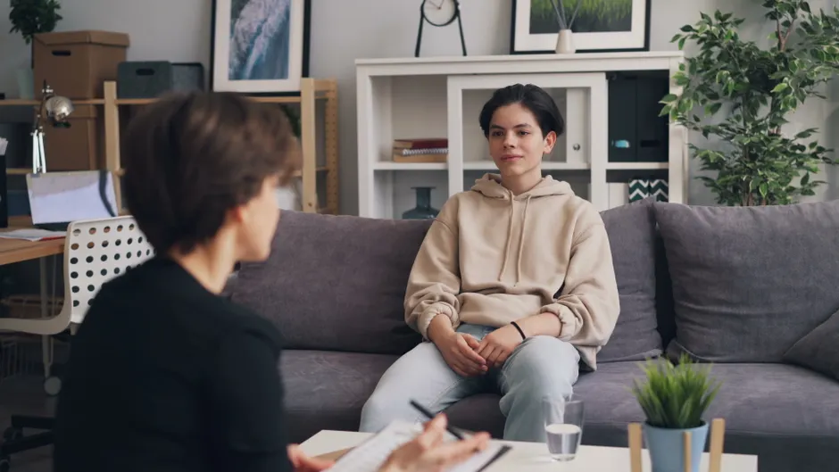 Teen undergoing therapy in modern office, showcasing supportive dialogue.