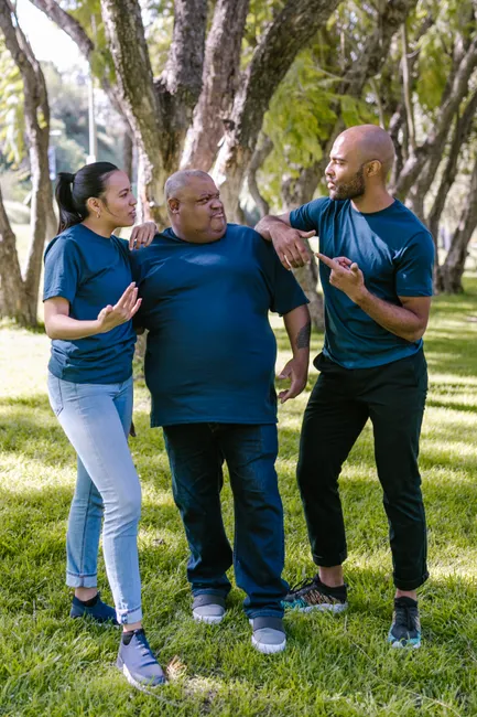 Three adults engage in friendly conversation and team building activities outdoors.