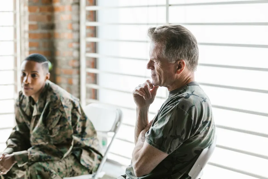 Two military veterans participate in a supportive therapy session, focusing on mental health and recovery.