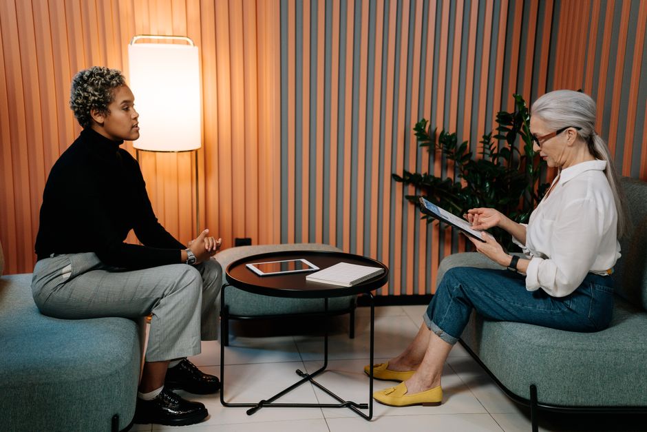 Two women engaging in a professional interview setting, using a tablet.