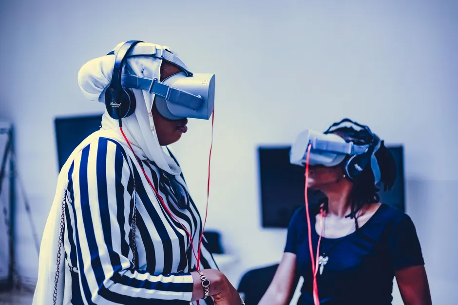 Two women using virtual reality headsets indoors, exploring immersive technology.